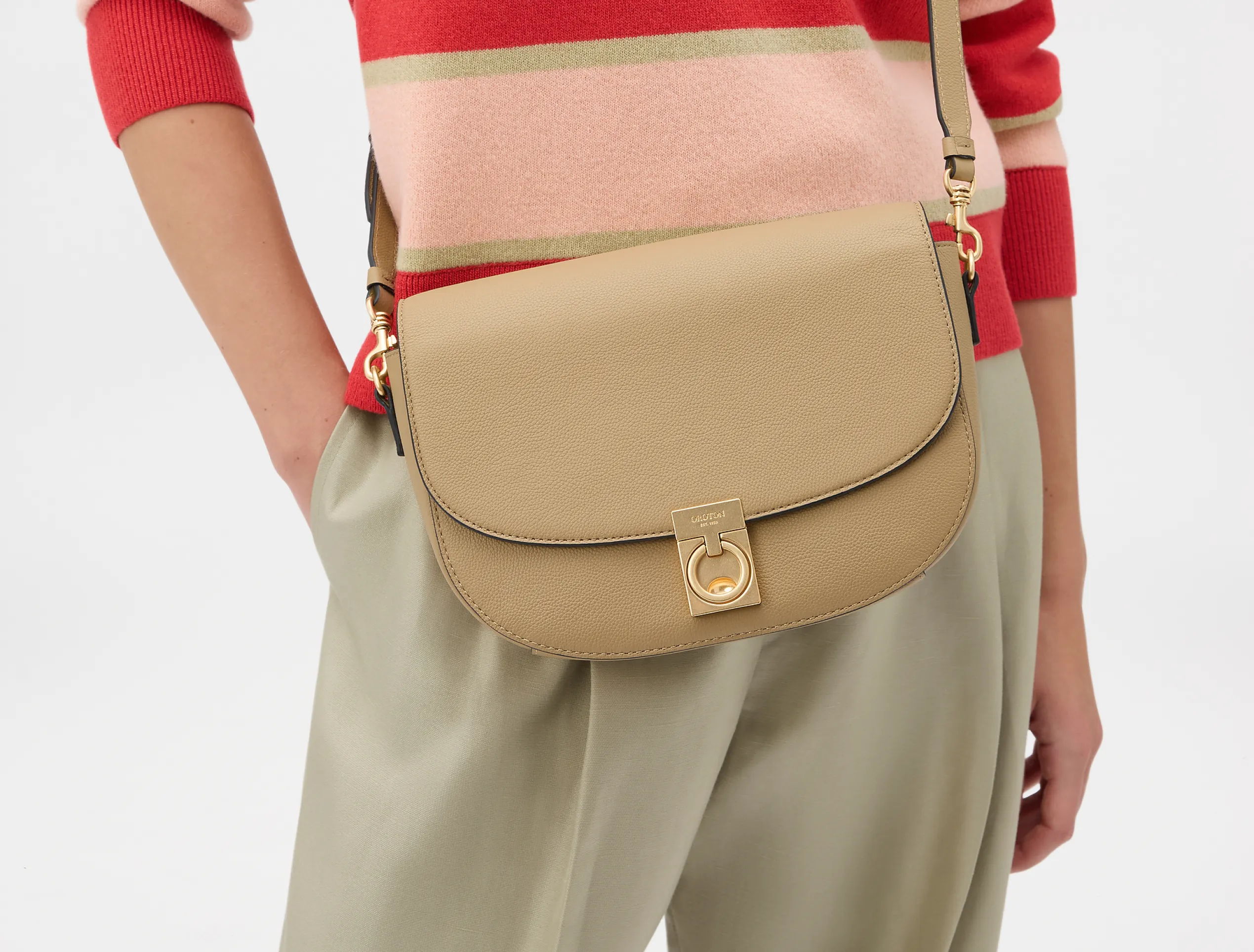 Person wearing a striped sweater with a beige crossbody bag.