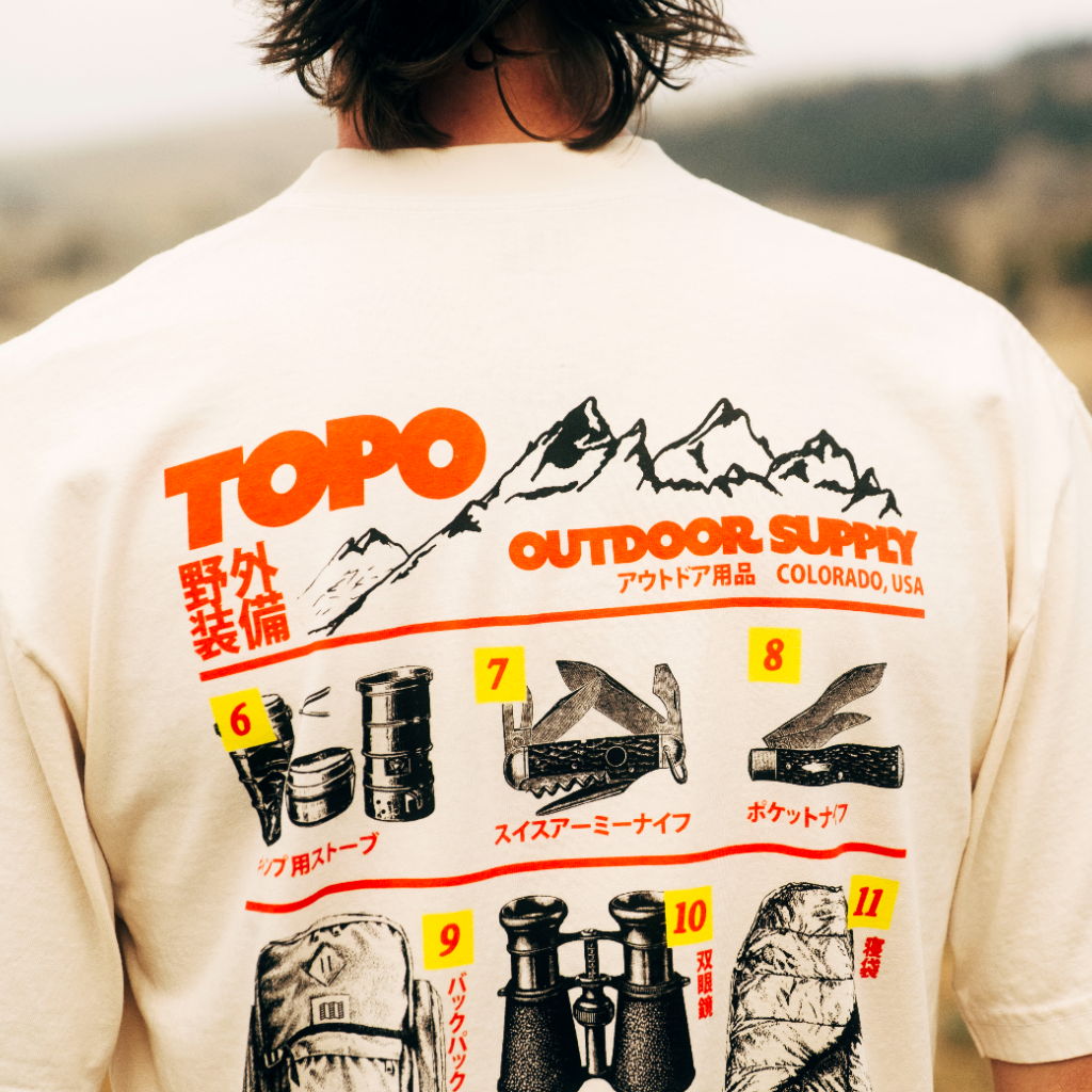 Person wearing a shirt with outdoor supply graphics and mountain illustration.