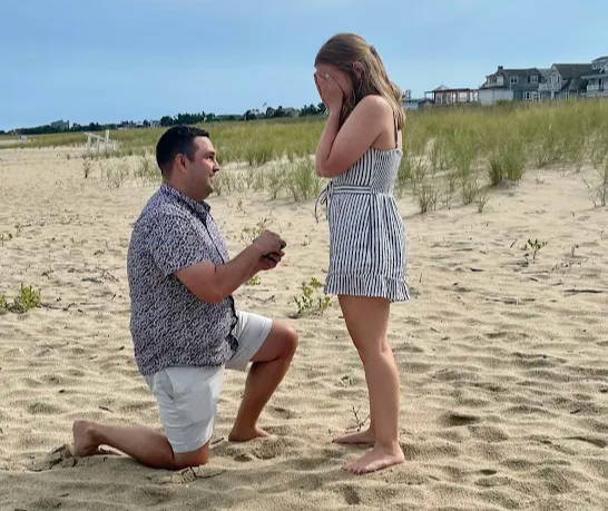 AJ on one knee proposing to Kristen on the beach