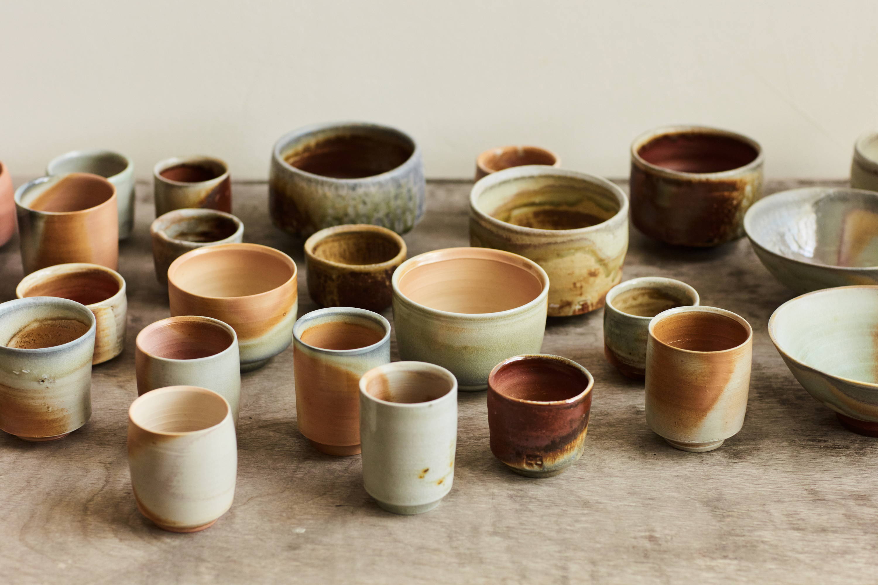 Collection of wood-fired tea cups and bowls on a wood table