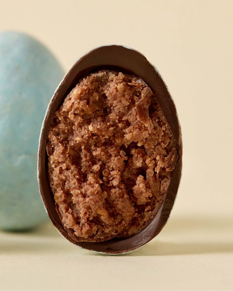Chocolate-covered treat with a textured filling, next to a blue candy.