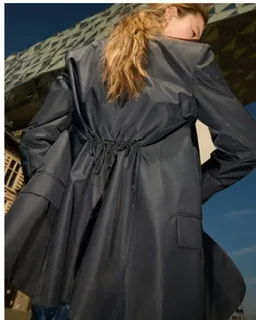 A woman in a stylish black coat, viewed from behind.