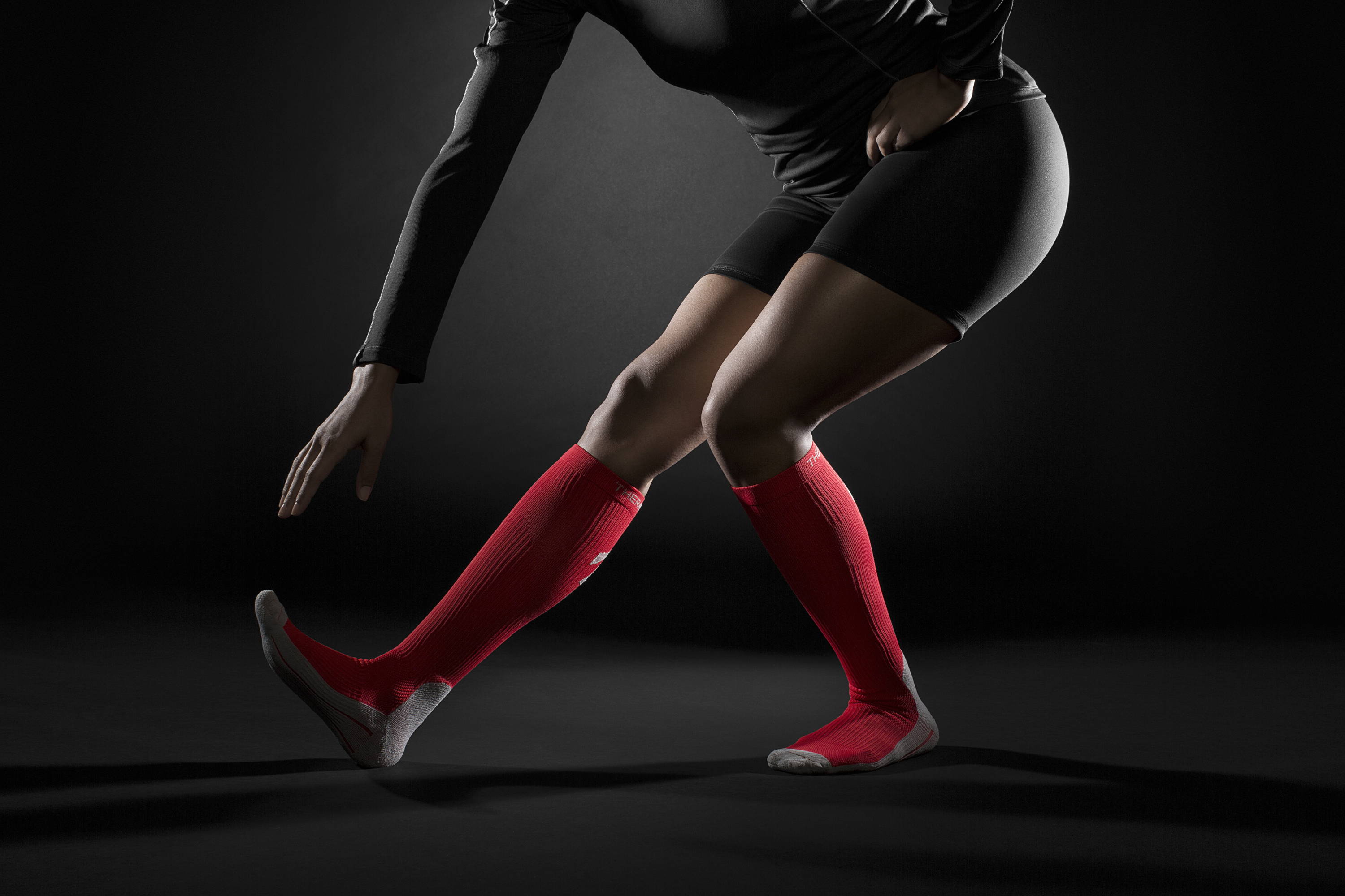 Female stretching indoors while wearing TheraSport Athletic Compression Socks