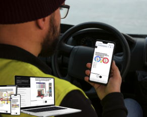 Person in a vehicle using a smartphone, with laptops shown in the foreground.