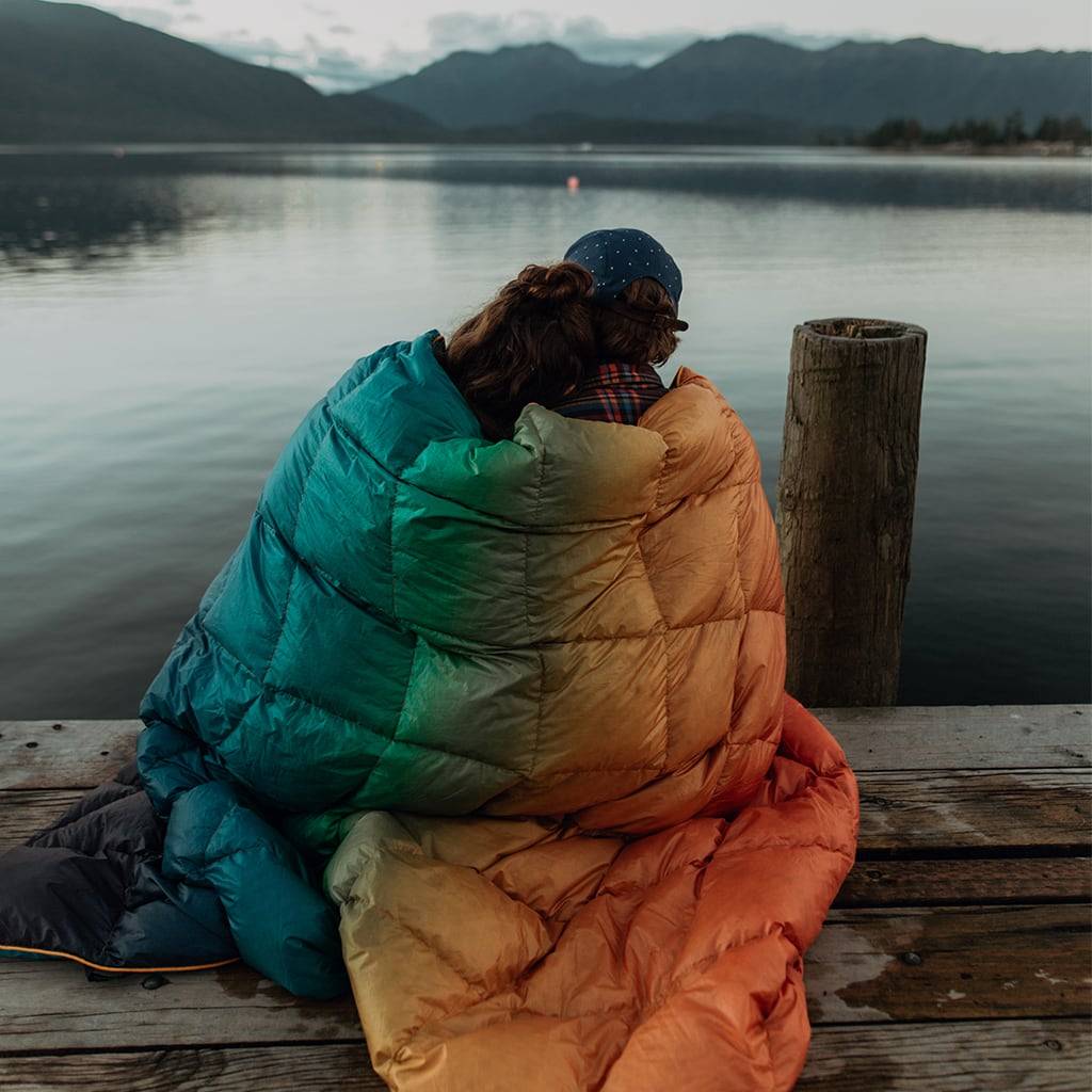 Man and woman wrapped in blanket on pier