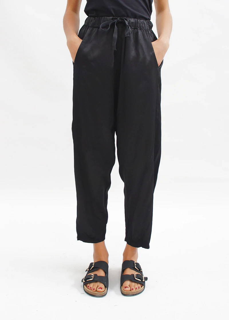 Model wearing black silky trousers with sandals