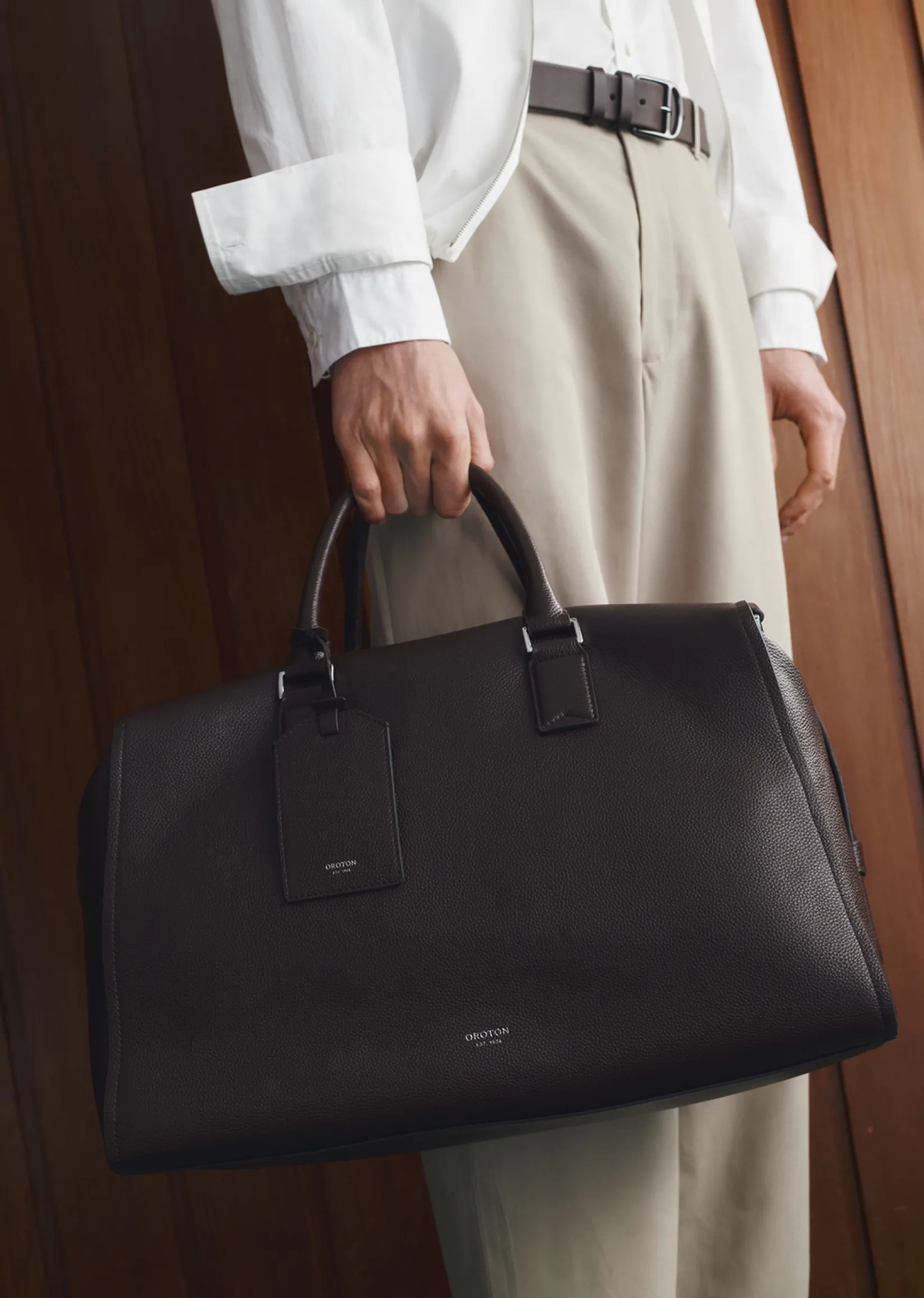 A person holding a stylish black leather bag.