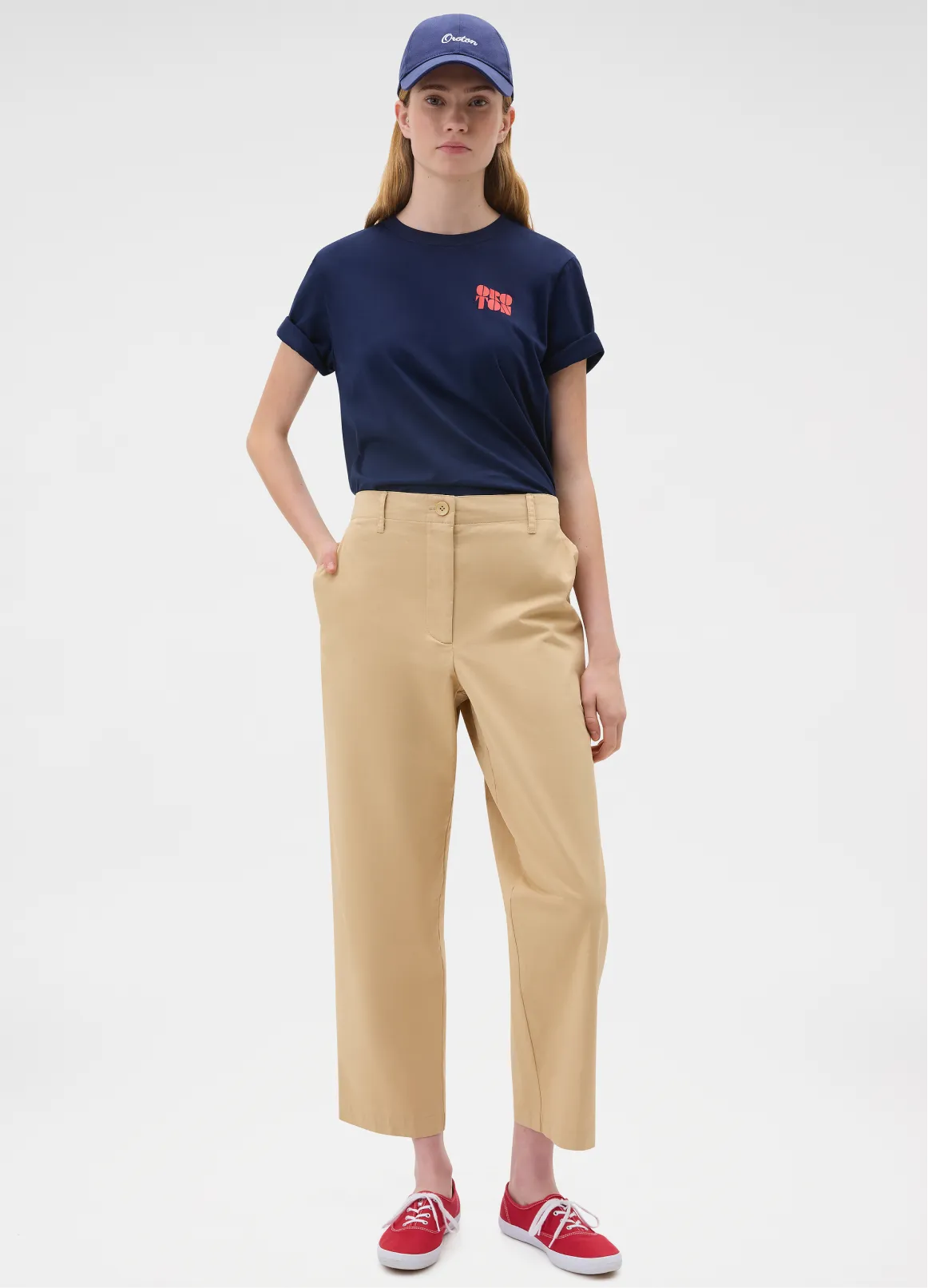 A person wearing a navy t-shirt, beige pants, and red shoes.