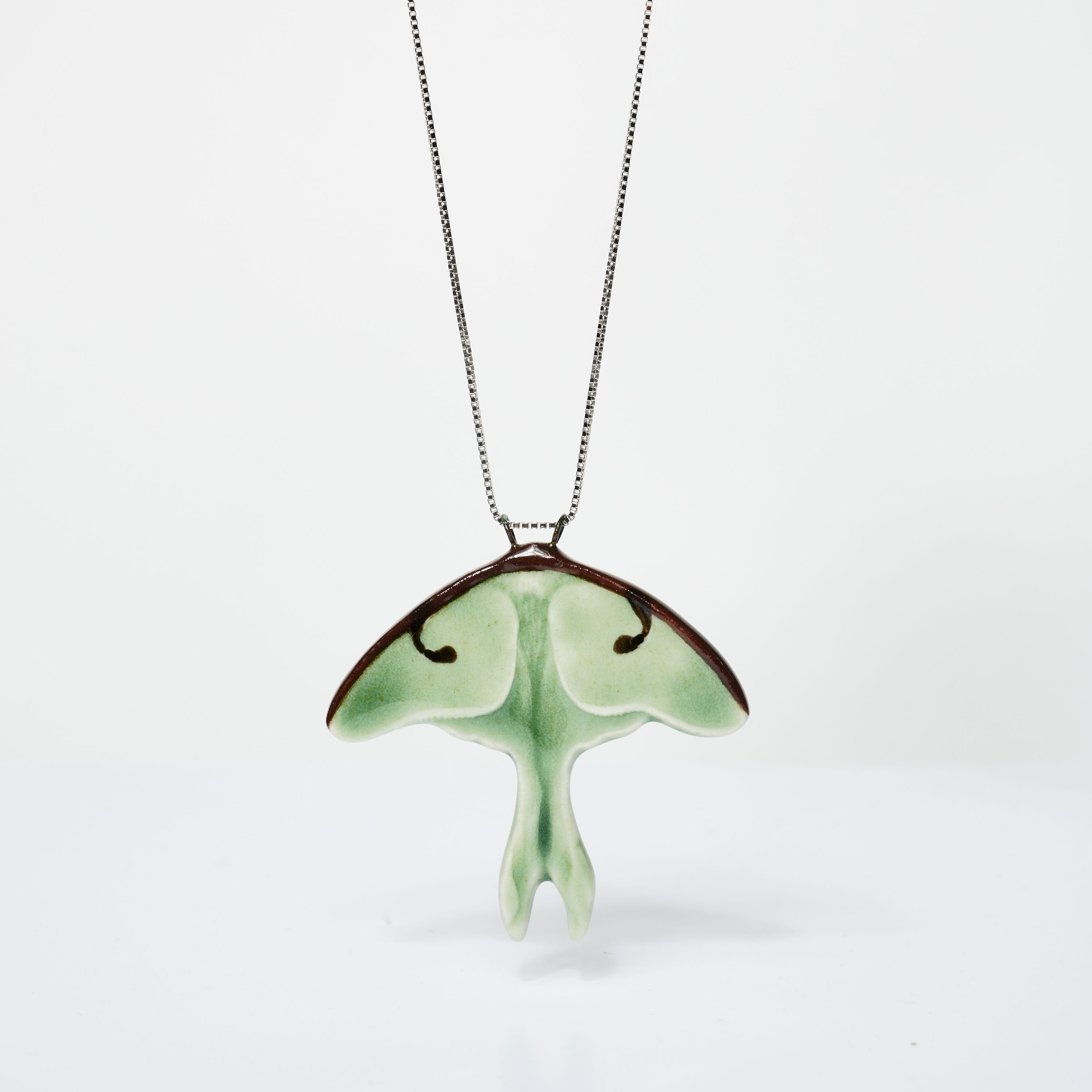A green ceramic pendant shaped like a moth on a silver chain.