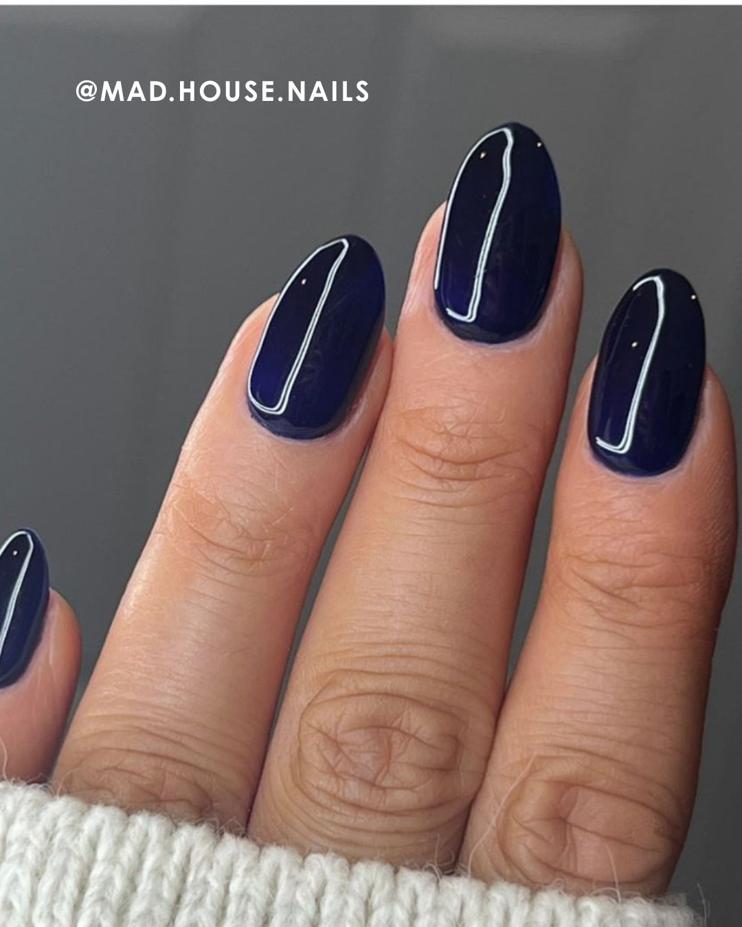 Close-up of manicured fingers with dark blue nail polish.