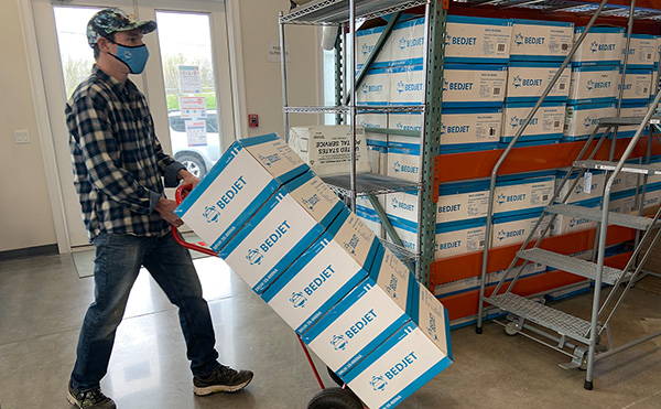 a man moving a stack of BedJets through a warehouse