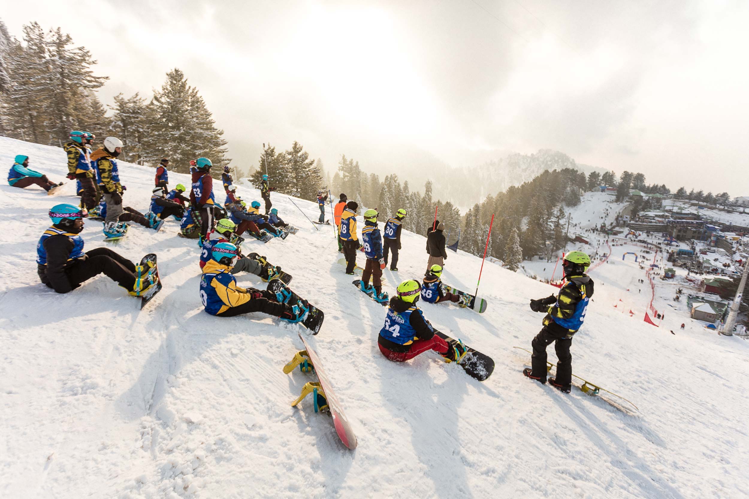 Skiers and snowboarders resting on a snowy slope during a winter day.