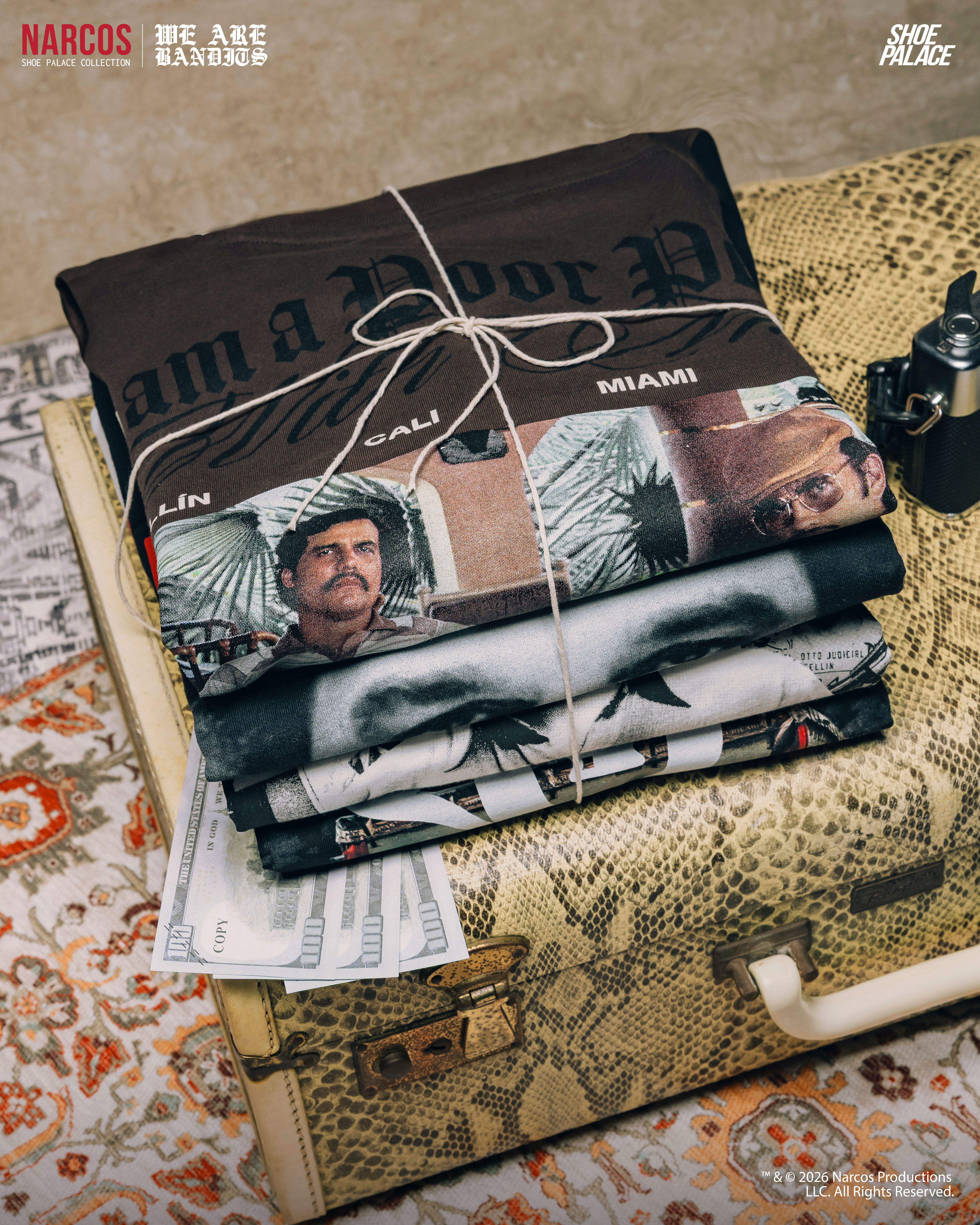 Stack of themed t-shirts tied with string on a patterned suitcase.
