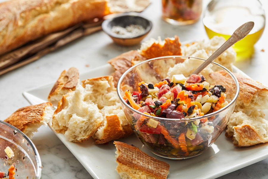 Muffaletta olive salad served in a glass bowl with bread