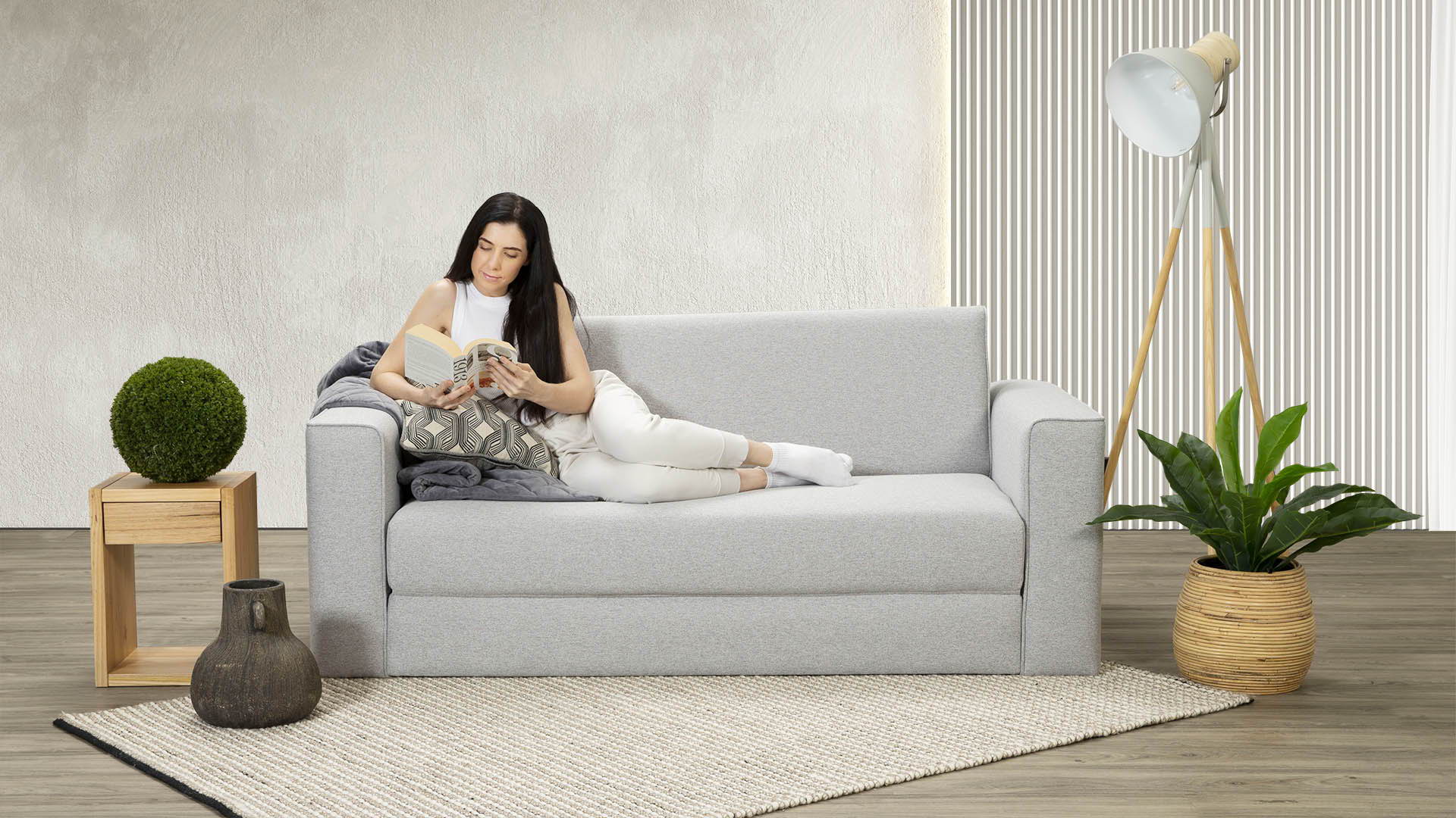 A woman lounging on a Zeek Sofa Bed.