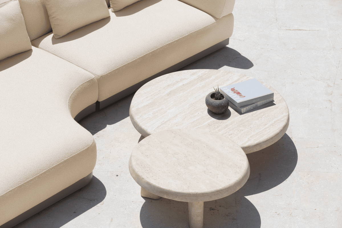 A serene outdoor living space featuring a soft white couch and a round stone coffee table.