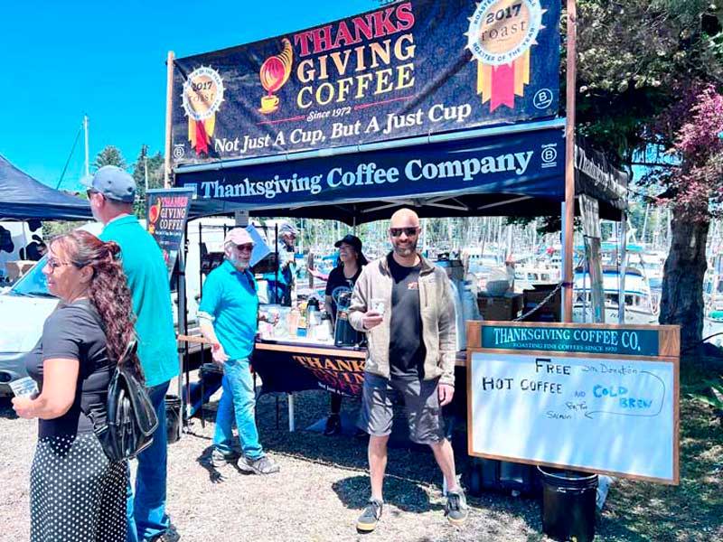 The Thanksgiving Coffee Booth with signs and banners at the Salmon BBQ with the CEO, Jonah Katzeff  out front. 