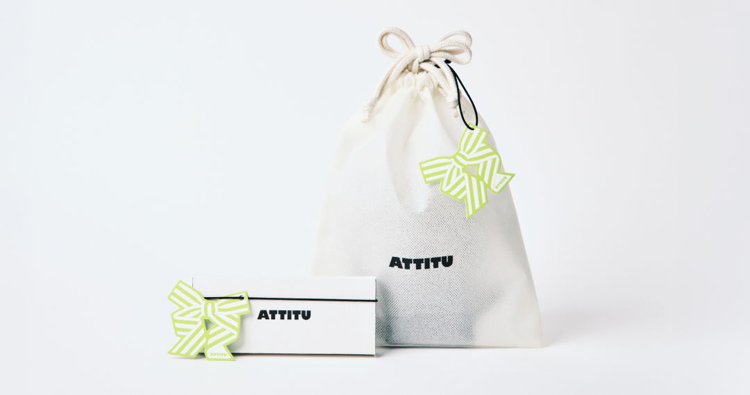 A gift bag with a green tag and a box beside it.
