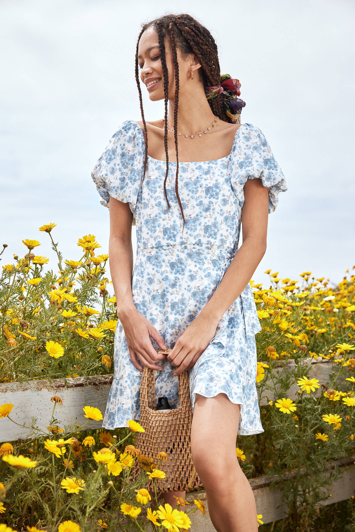 Trixxi sun-kissed summer lookbook, girl withyellow sunglasses, blue printed floral dress in field of yellow flowers. 