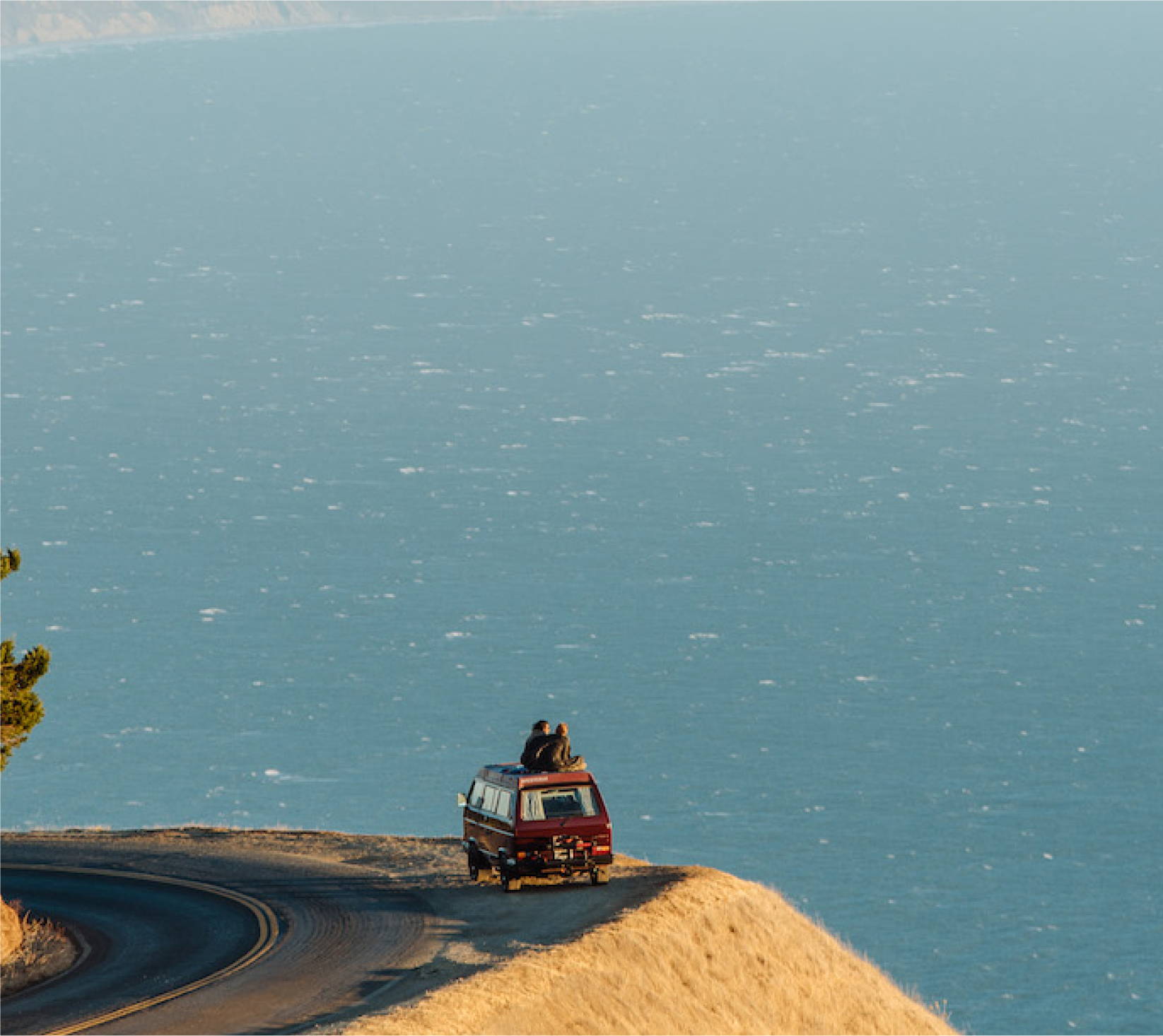 a van on a road on a cliff with a body of water in the background