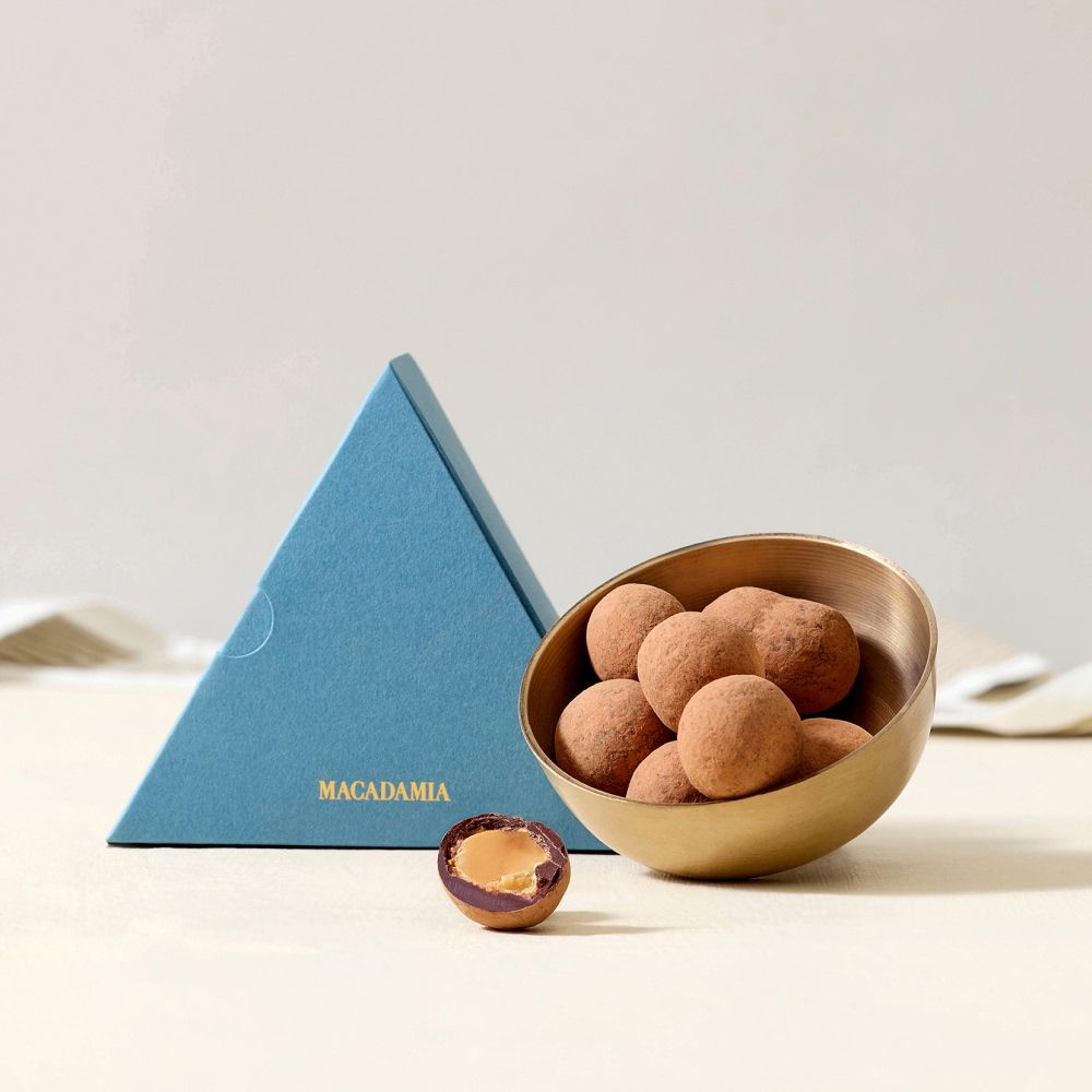 Chocolate truffles in a bowl next to a blue triangular box.