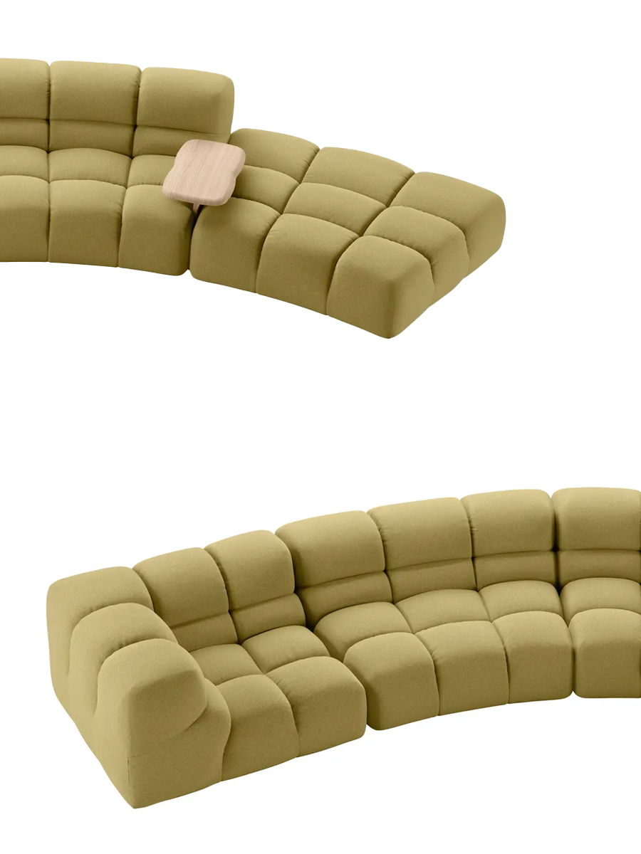 Curved beige sectional sofa with tufted cushions and a small pillow.