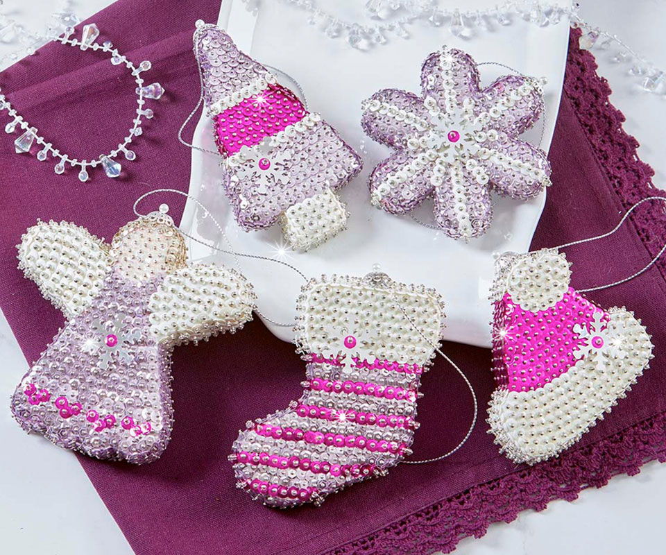 Colorful handcrafted ornaments on a white cloth with a purple background.