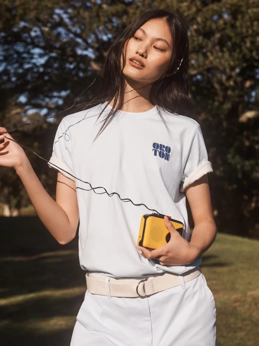 A woman in a casual outfit holding a yellow bag outdoors.