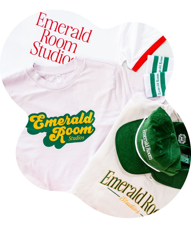 Collection of Emerald Room Studios branded merch including screen printed t-shirts with the logo in red serif text and yellow retro script, embroidered green cap and cream sweatshirtt, and green and white woven socks