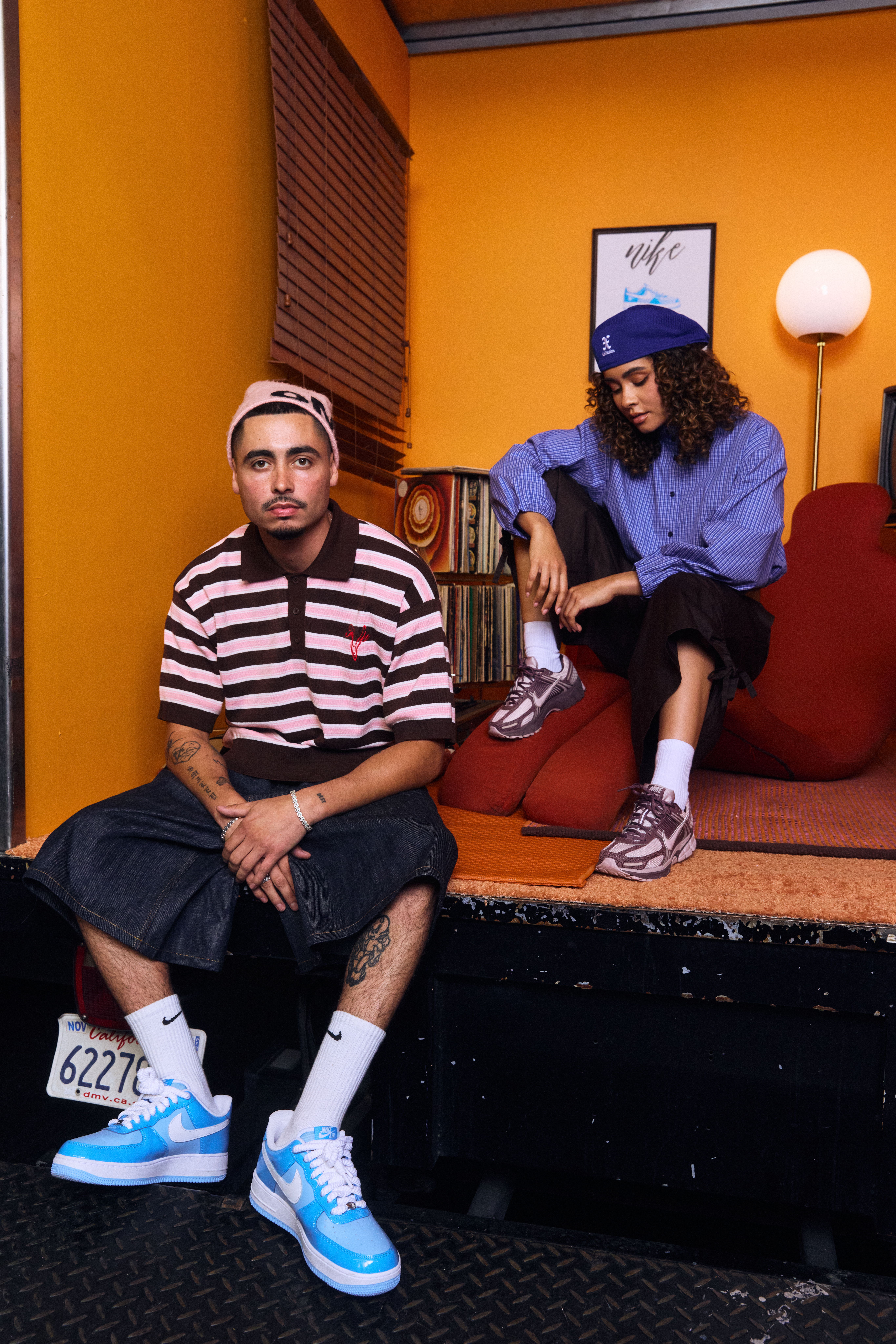 Two people in casual outfits pose in a colorful room.