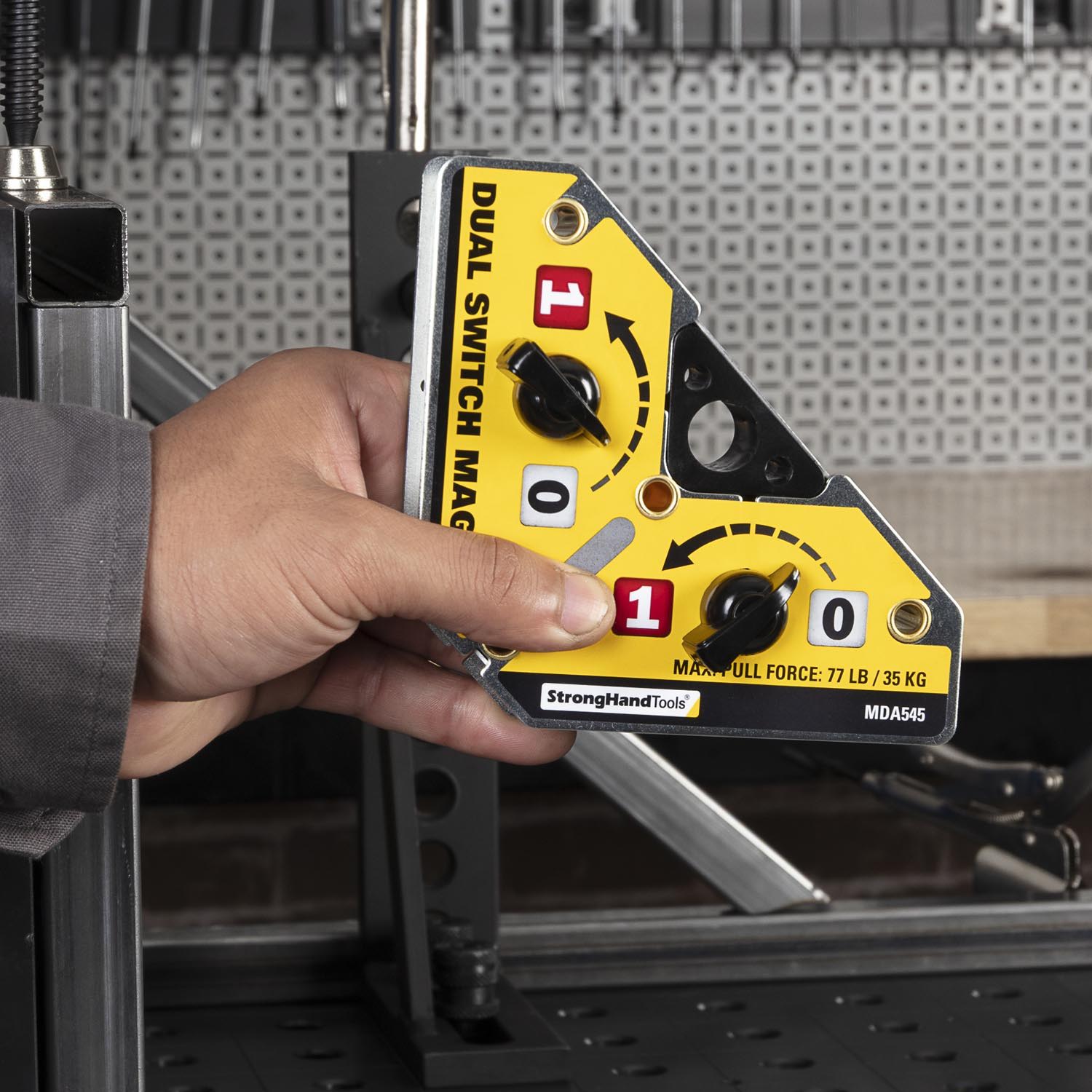 Hand holding a yellow and black dual switch magnetic tool.