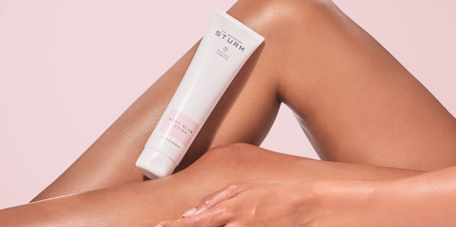 Cream tube on smooth, tanned legs against a pink background.