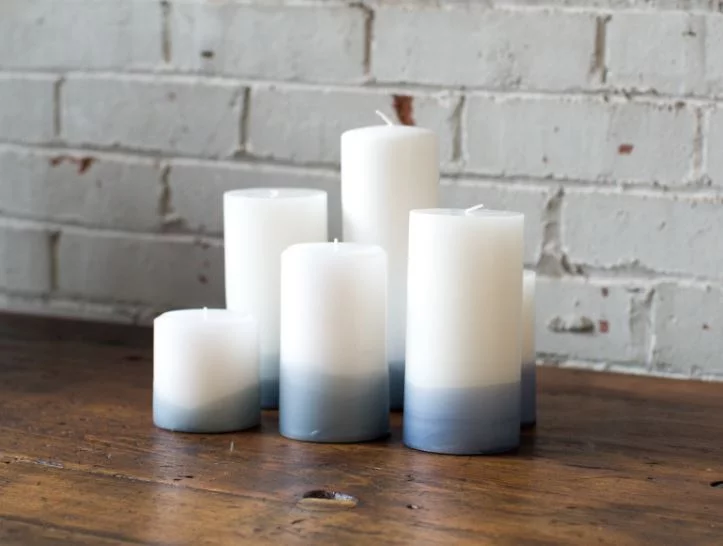 Five candles with a gradient from white to blue on a wooden surface.