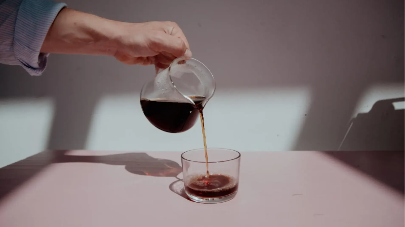 Filterkaffee wird aus einer Karaffe in ein Glas eingegossen