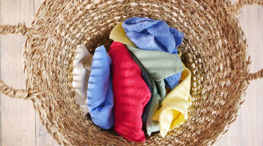 a wicker laundry basket with different colored towels inside