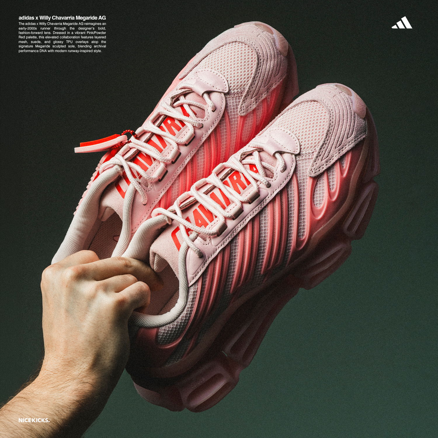 Hand holding pink Adidas sneakers against a dark background.
