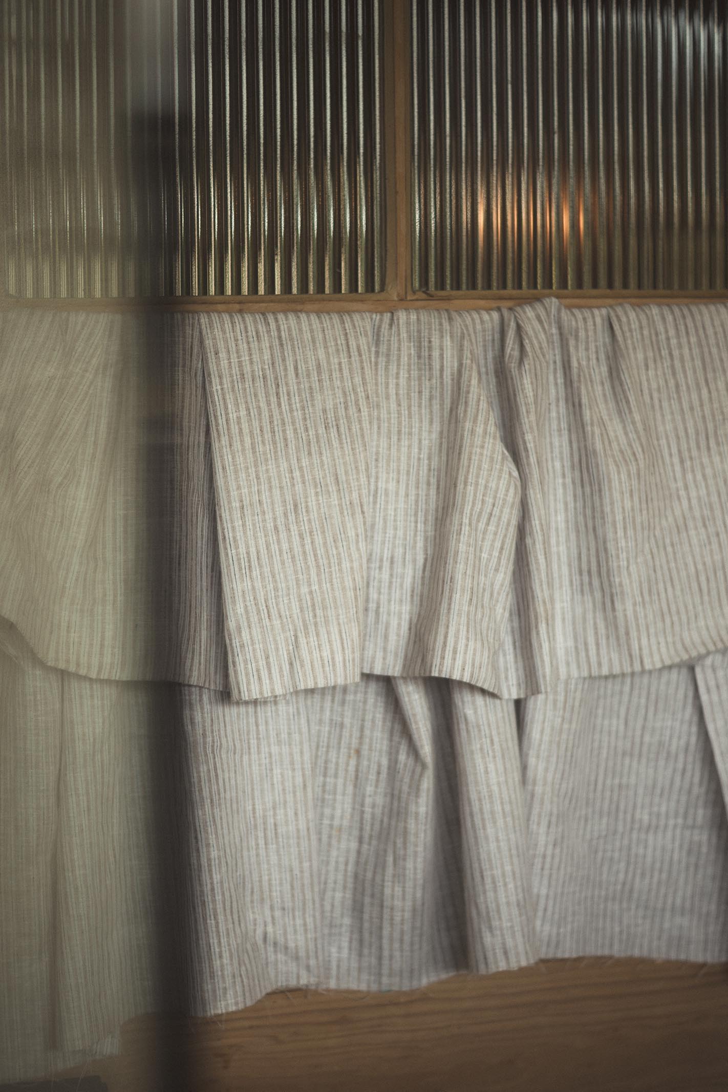 Curtains with a striped pattern hanging in front of a wooden surface.