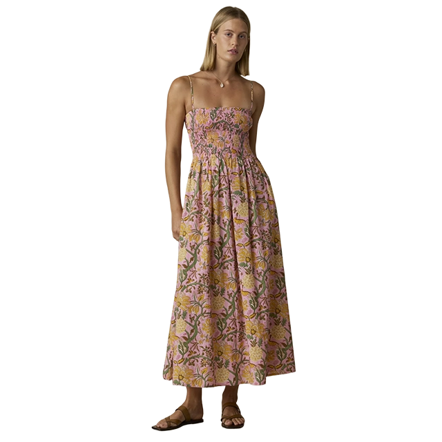Woman wearing a floral maxi dress, standing against a plain background.