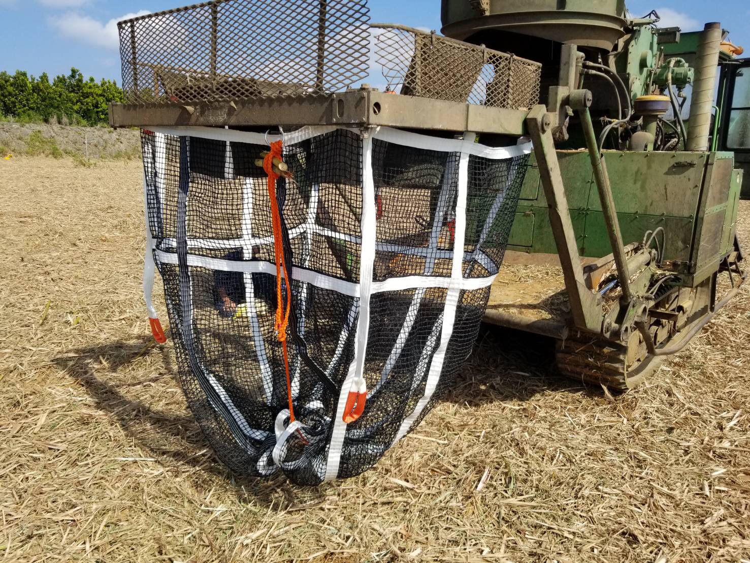 Agricultural equipment attachment on a field, used for harvesting or collecting.