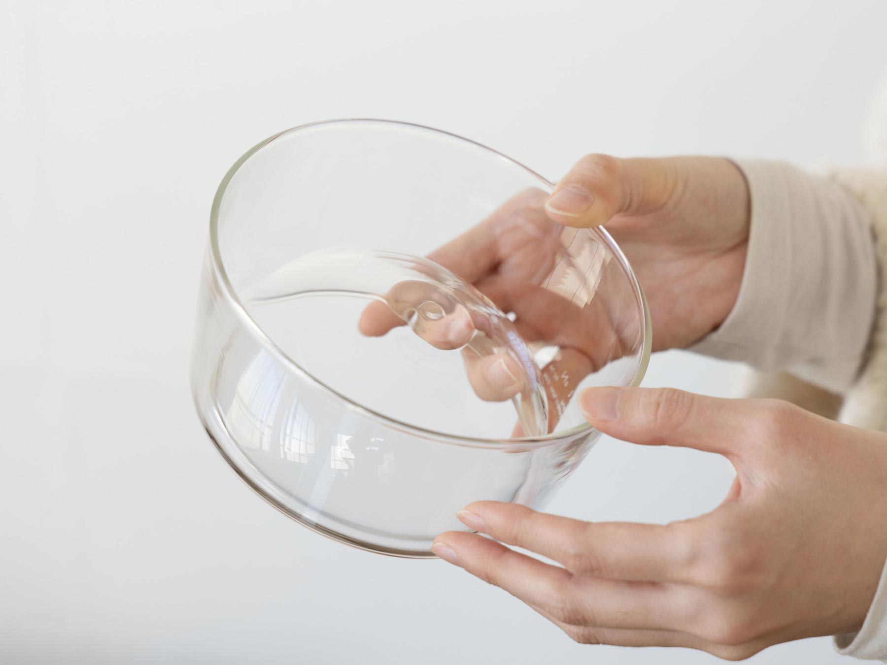 A person holding a clear glass bowl.