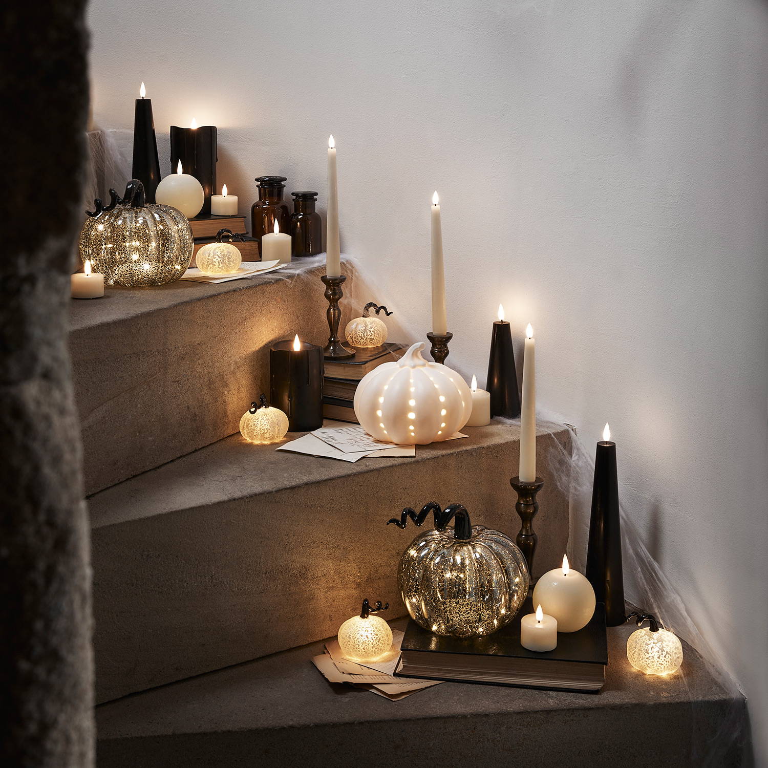 A Halloween staircase with pumpkins of varying sizes and black and ivory LED candles.