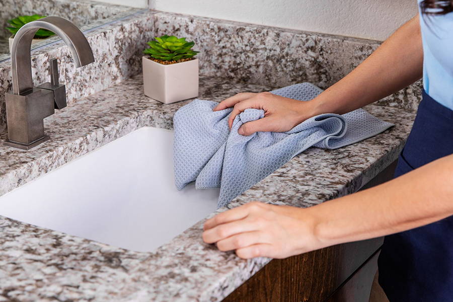 a professional cleaner cleaning a bathroom sink with a waffle weave microfiber towel