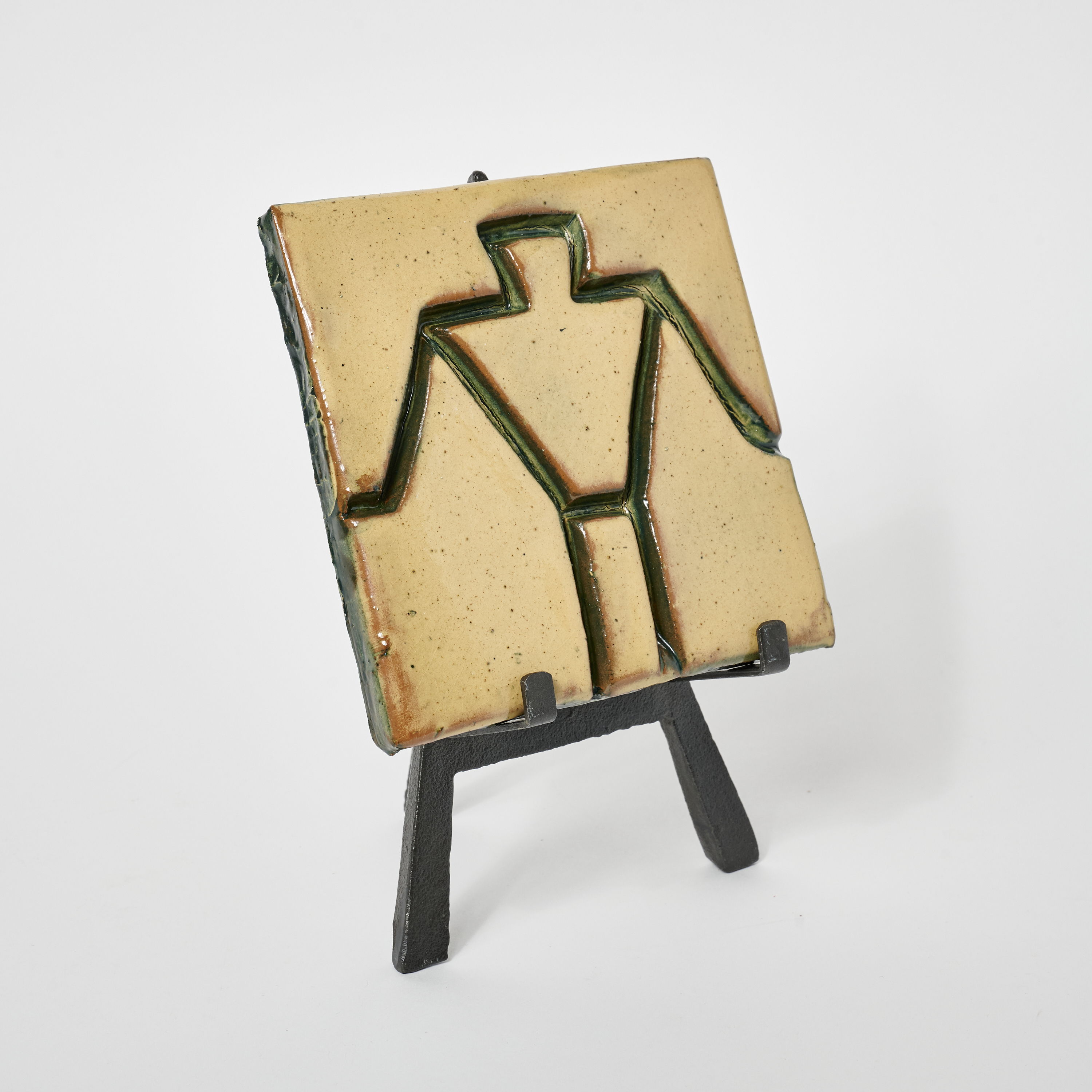 A textured plaque featuring a human figure design on a stand.