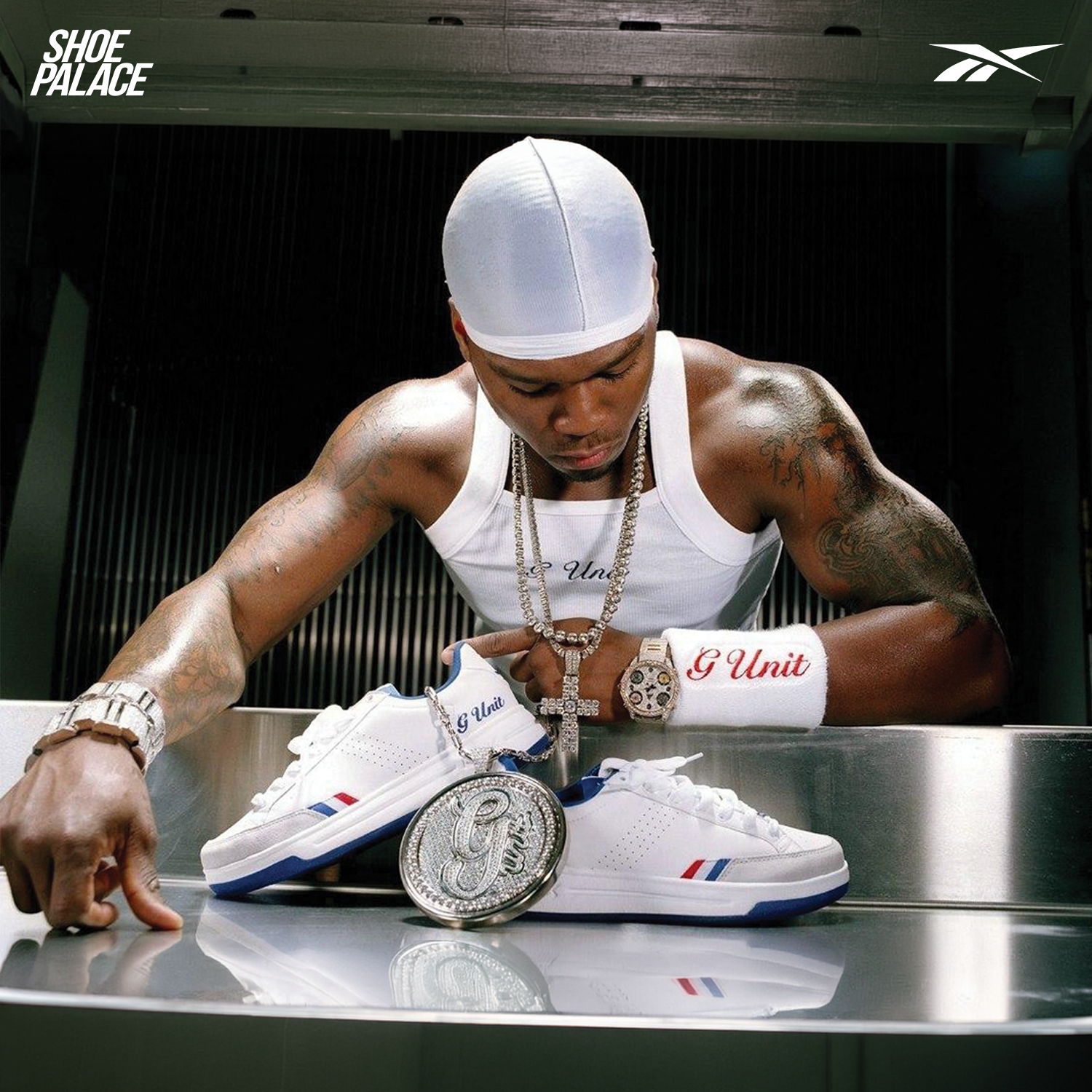 Person examining white sneakers with jewelry and wearing a white tank top.