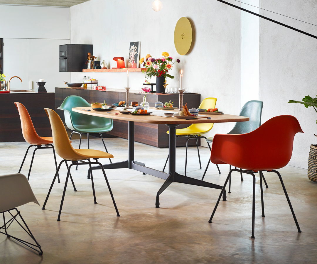 Colorful Eames Shell chairs by Vitra around a modern dining table in a bright room for top 10 dining chair blog.