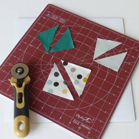 Little pieces of fabric on a rotating cutting mat with a rotary cutter