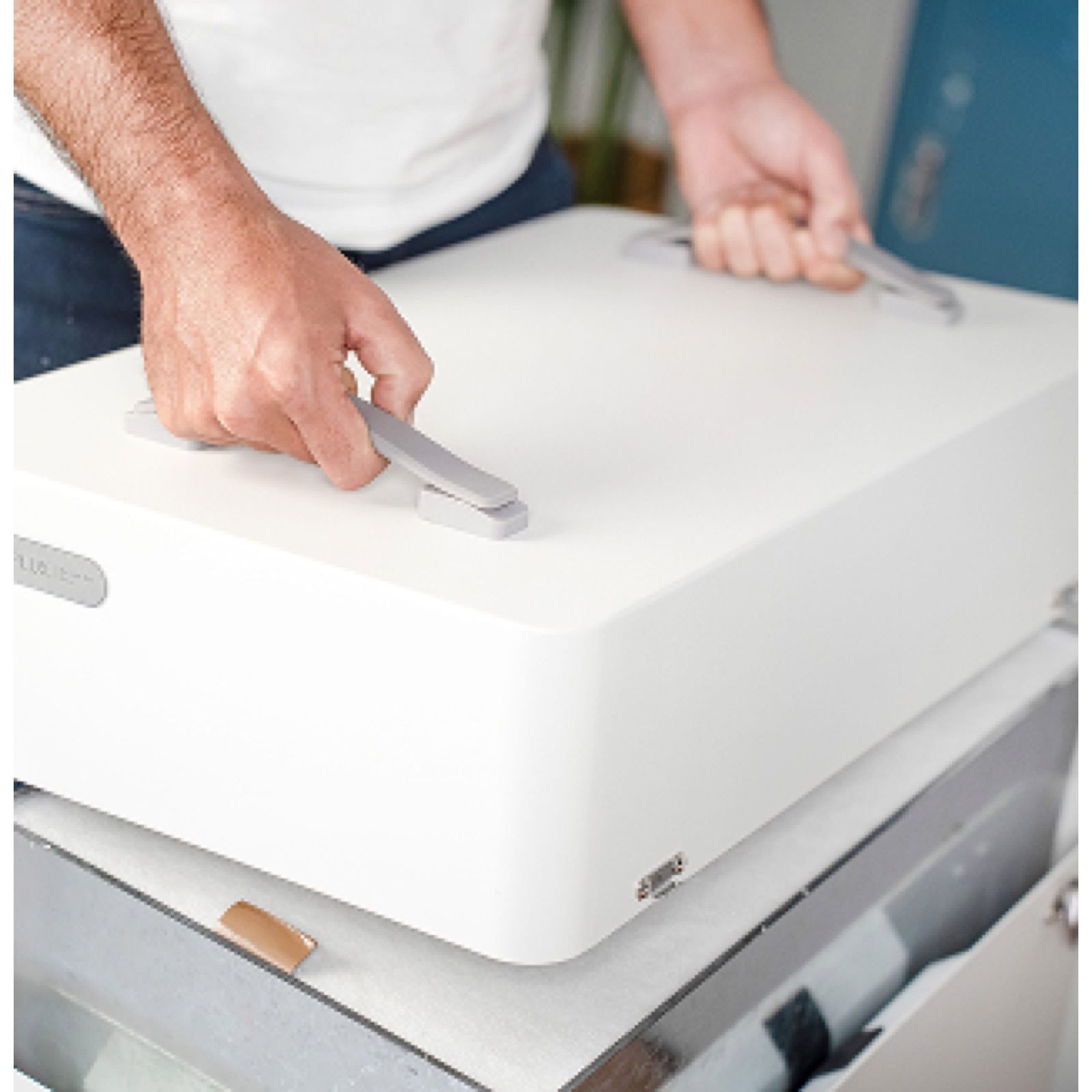 Person lifting a white box with handles.