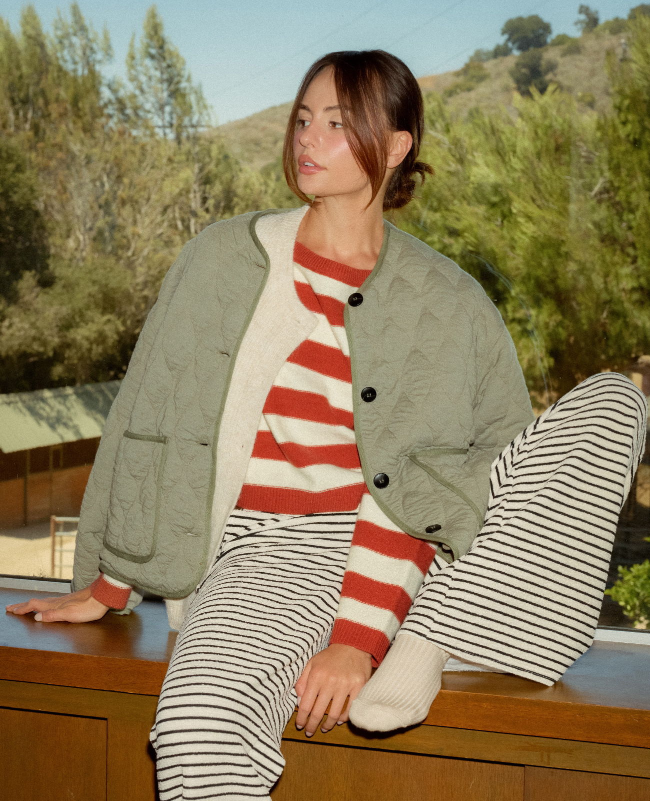 Person in casual outfit sitting on a ledge with a scenic background.