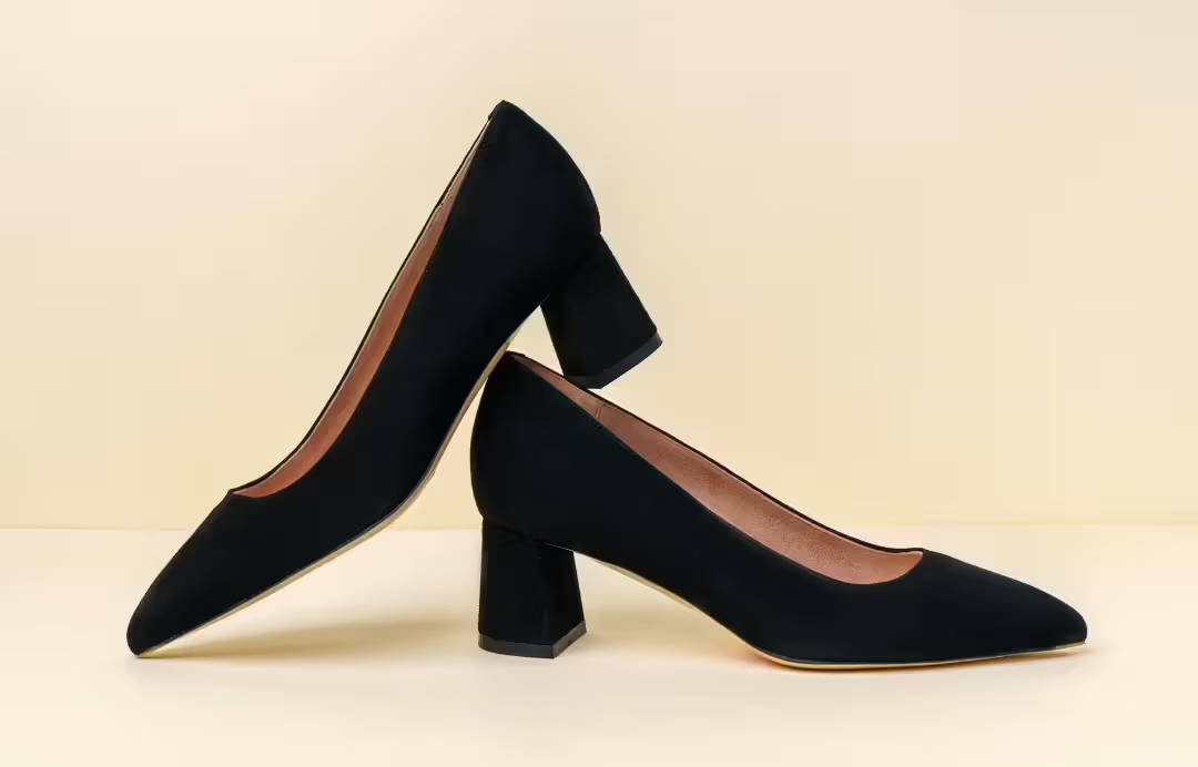 A pair of black suede high heel shoes on a neutral background.