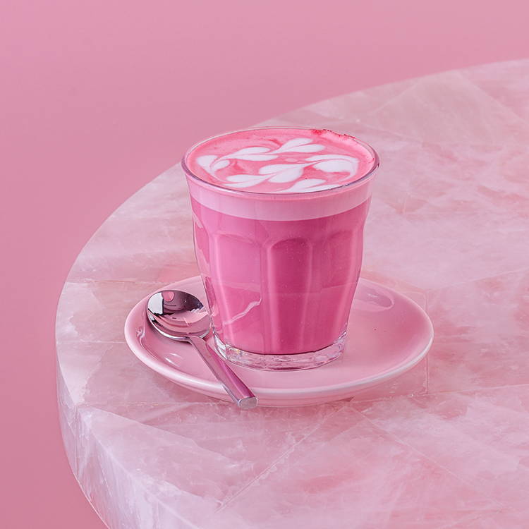 Pink latte in a glass on pink table